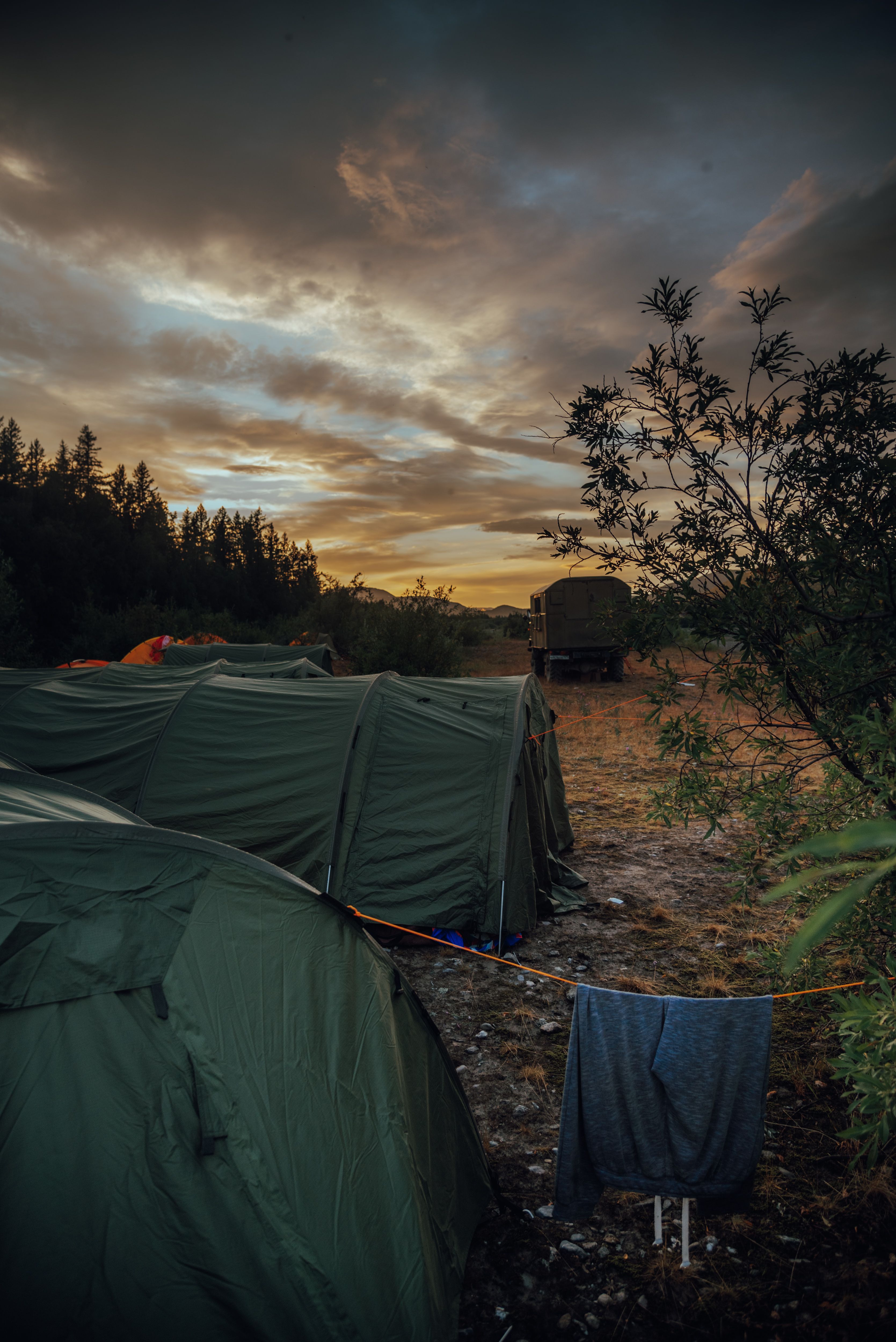 Tents pitched at sunset with a truck in the distance
