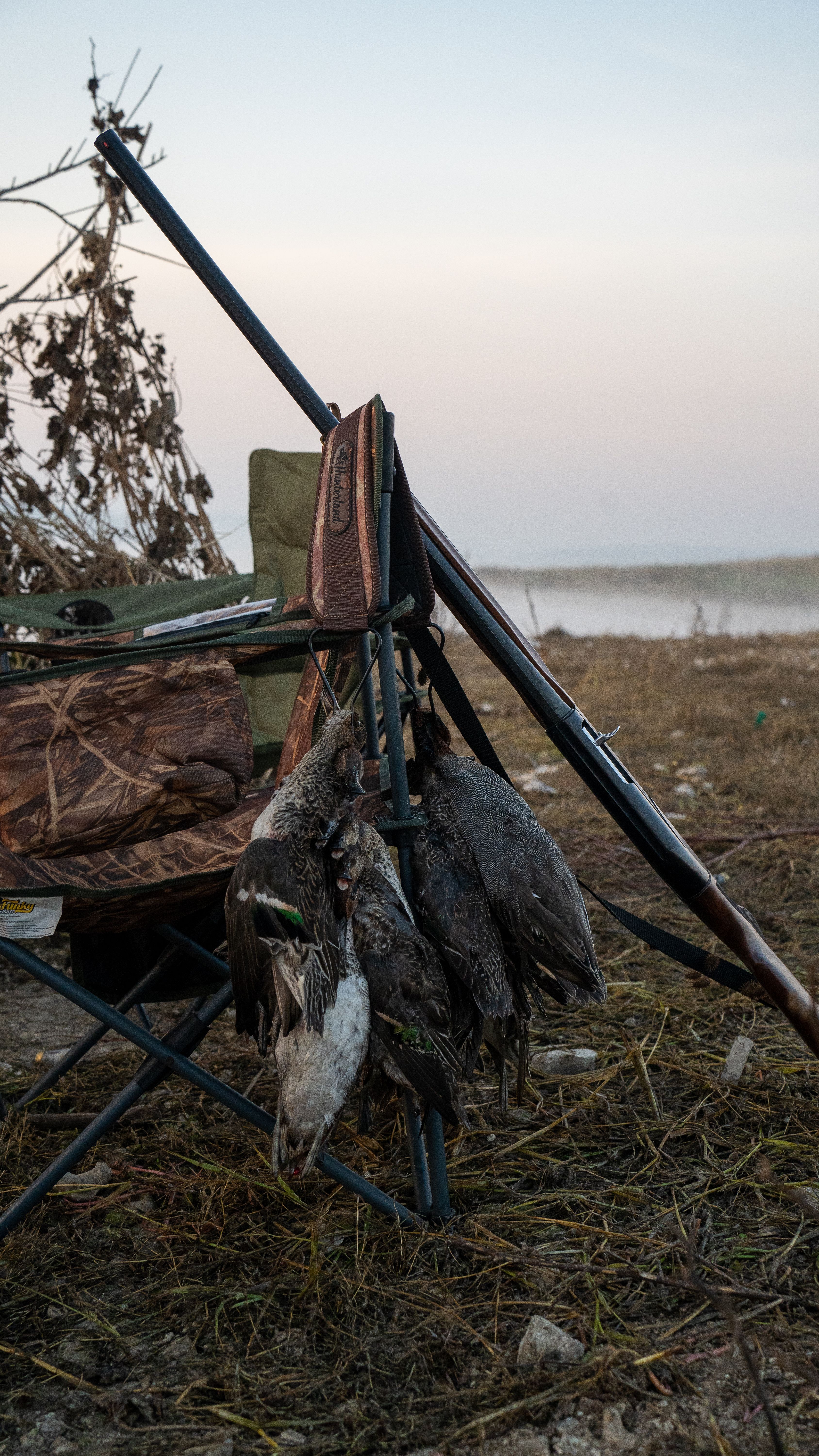 Shotgun and waterfowl at a duck blind at dawn